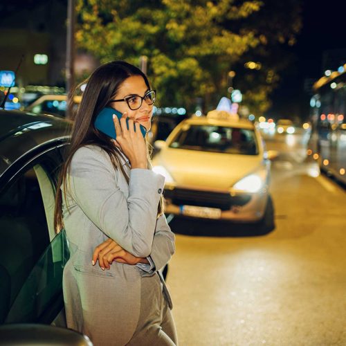 woman standing in line calling a taxi